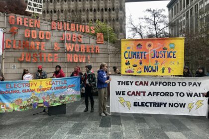Banners at a climate justice rally. Banner read, "Green Buildings, Good Jobs, Climate & Worker Justice Now!" "They Can Afford to Pay. We Can't Afford to Wait. Electrify Now!" "Electrify Seattle: Cooling, Clean Energy, Union Jobs" "Climate Justice Now!"