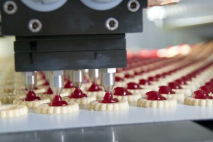 Production line of shortbread cookies being filled with jelly by a robot