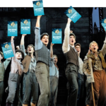 Newsies on Broadway holding the book "Ralentir ou Périr"